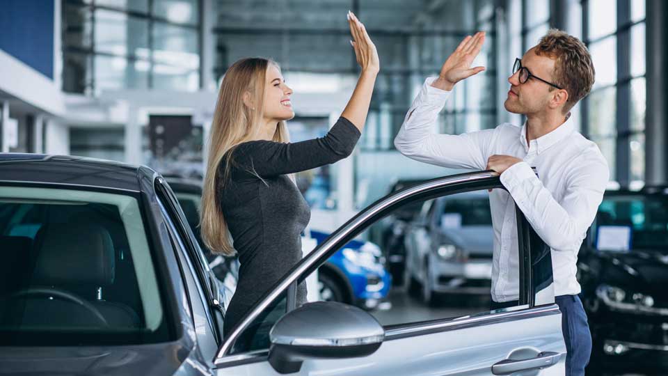 Käufer und Verkäufer geben sich ein High Five nach dem Auto verkaufen im Autohaus